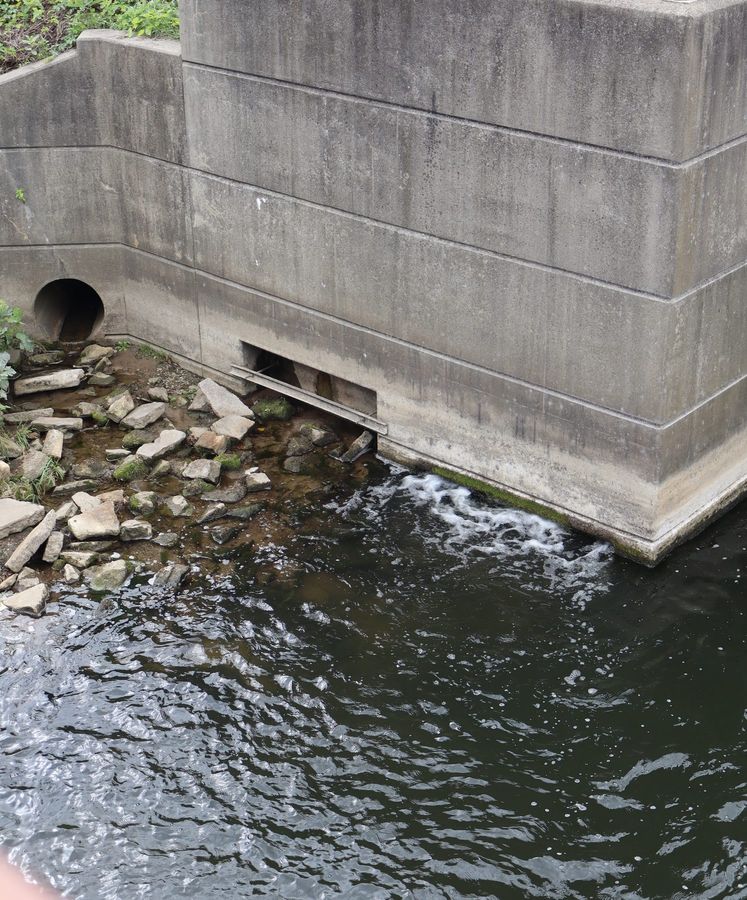 Water moving past a concrete pier, rocks at its foot